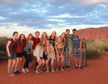 High school students smiling with the red mountains of Australia behind them