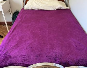 A twin-size bed with a purple blanket on top