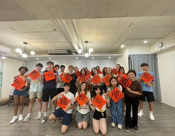 group photo with calligraphy teacher holding up their finished calligraphy 