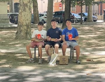 three students sitting on a bench in the park