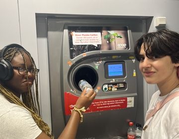 Two students using a recycling machine at a grocery store to receive "pant" money back.