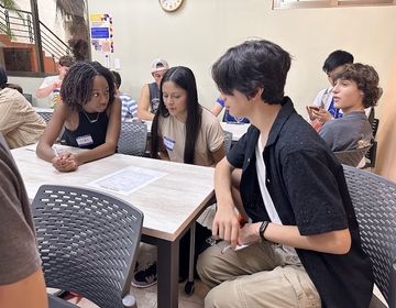 Three students sit around a table viewing a map of Merida, Yucatan. 