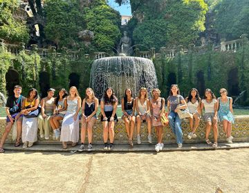 Students sitting in front of fountain in Rome