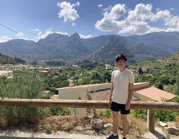 High school student posing in front of a scenic mountain abroad