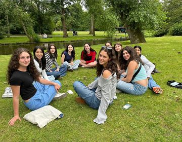 Group of teen participants sitting on the grass by a river 