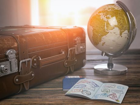 Globe and passport beside luggage on desk