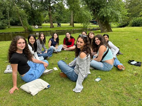 Group of teen participants sitting on the grass by a river 