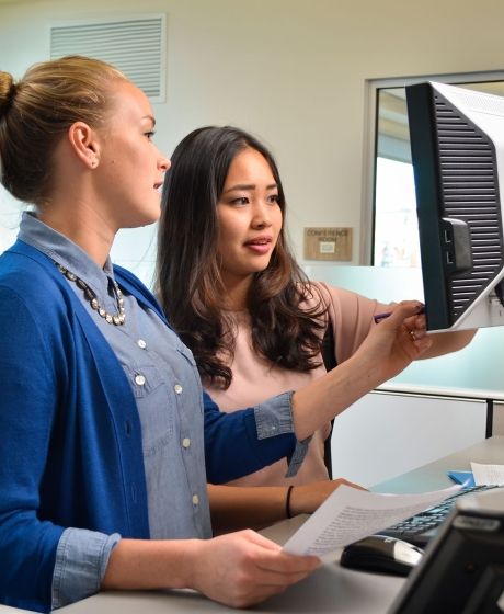 intern working with a professional at a computer terminal