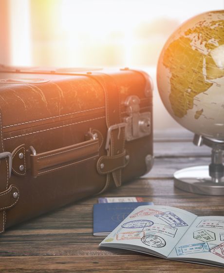 Globe and passport beside luggage on desk