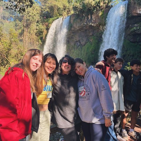 High school students on program posing in front of a waterfall