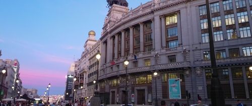 An image taken of a building on a main street in Madrid during sunset. 