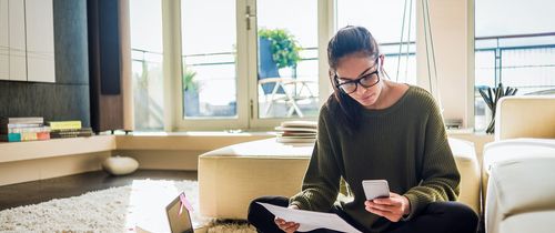 Young woman on her phone with her laptop out before her