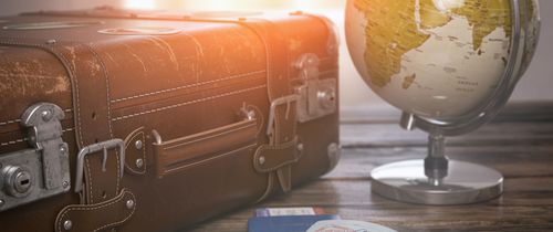 Globe and passport beside luggage on desk