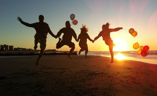people jumping on beach sunset