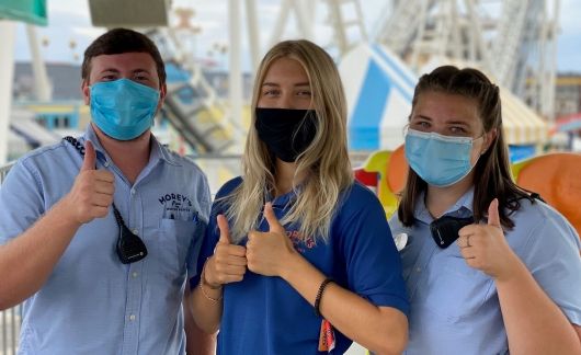 work and travel employees at amusement park wearing masks