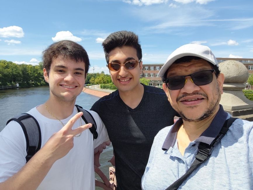 Three males posing by water 