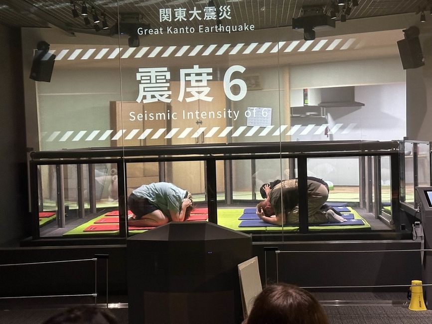 Global Navigators experience the shaking that affected Tokyo during the Great Kanto Earthquake. They are performing the "roly-poly pose" which is meant to protect them during an earthquake.