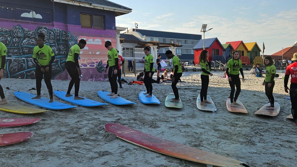 students standing on surfboards on the beach 