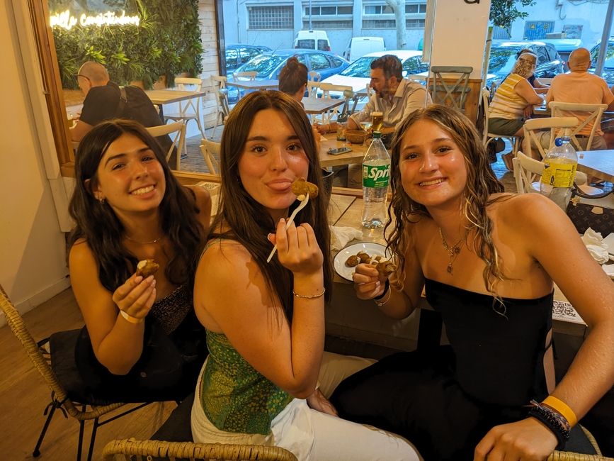 Three girls hold up food and smile