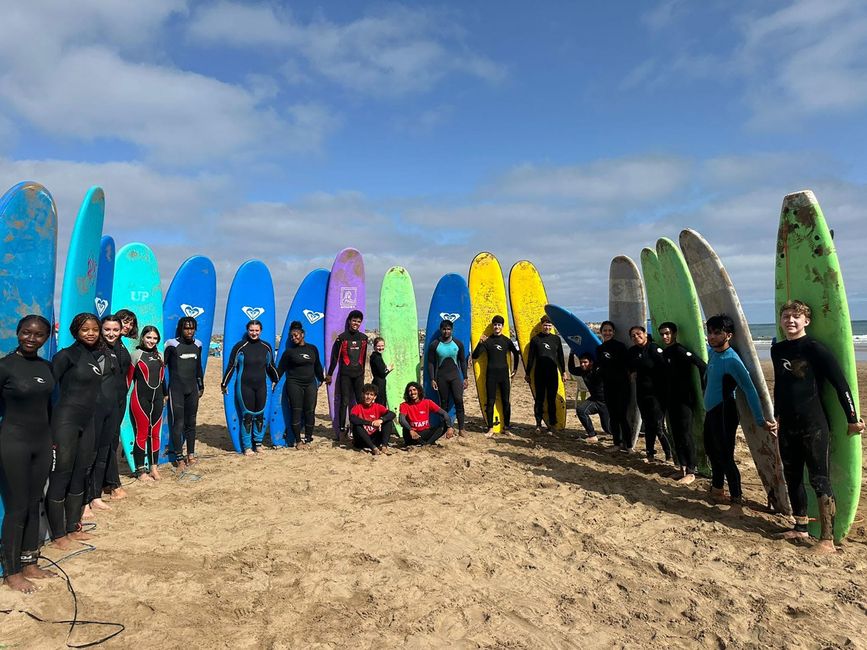 High school participants on beach with their surfboards