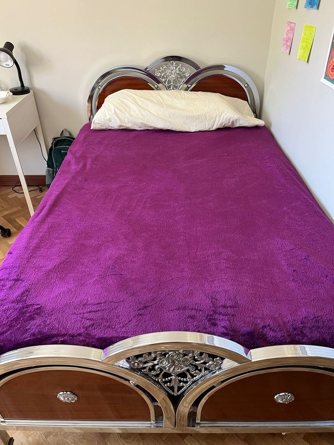 A twin-size bed with a purple blanket on top