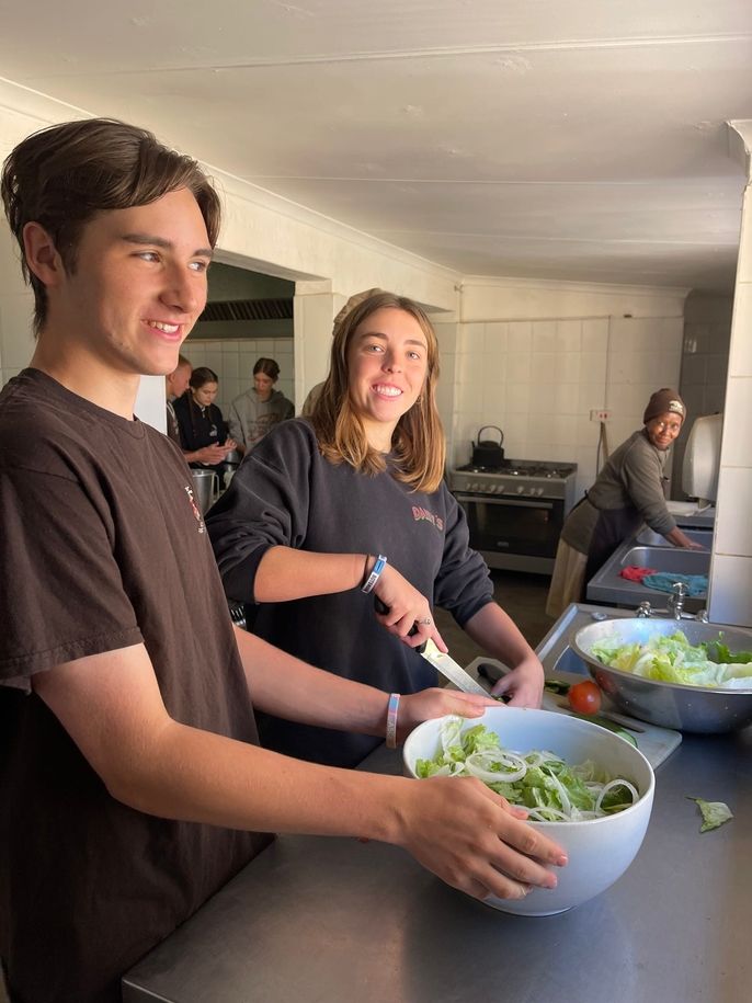 Putting together the salad: chopping onions, cucumbers, peppers, and tomatoes. 