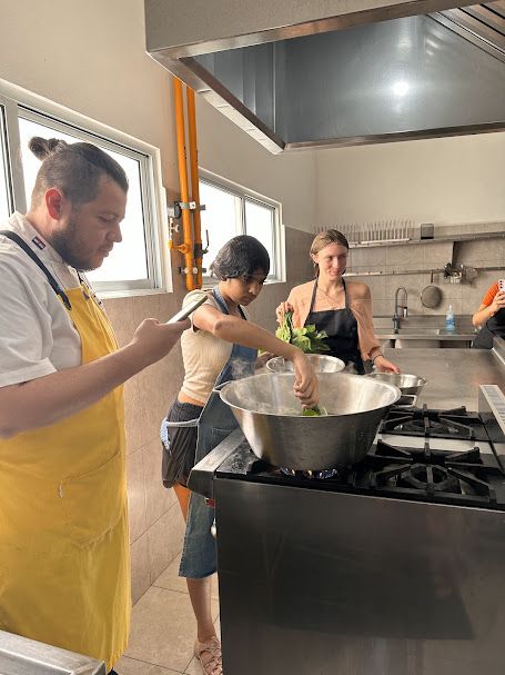 two students stand over a stove as they participate in a cooking class