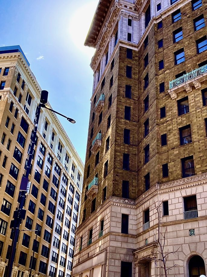 Two old buildings next to each other, the sun shines through the middle of them but is hidden.