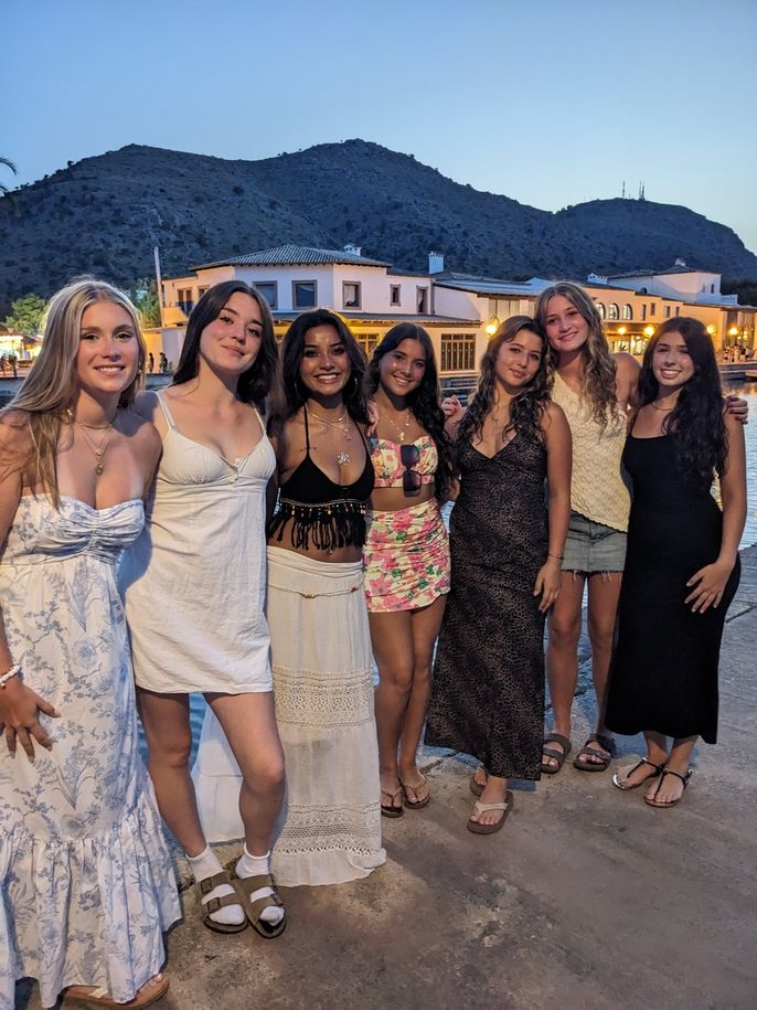 Seven students posing for a picture together in front of a lake