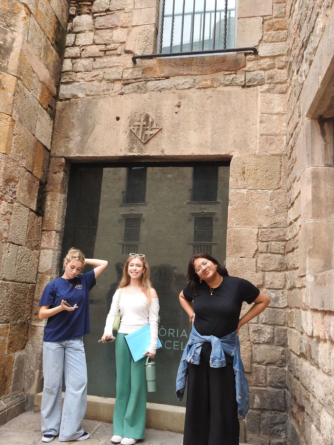 Students and adult standing by stone building posing for camera