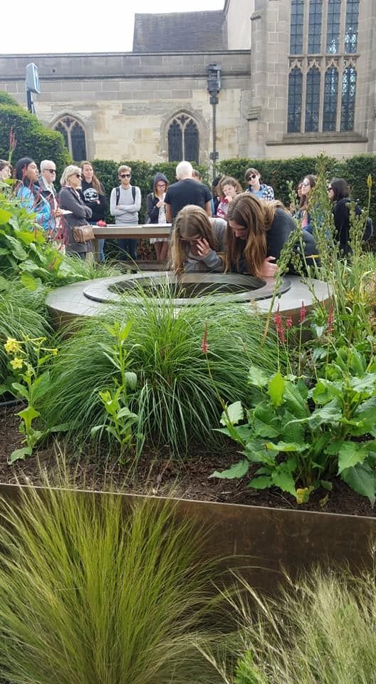 Raina and Brooke look into the welll, while the group behind listen about the history of New Place