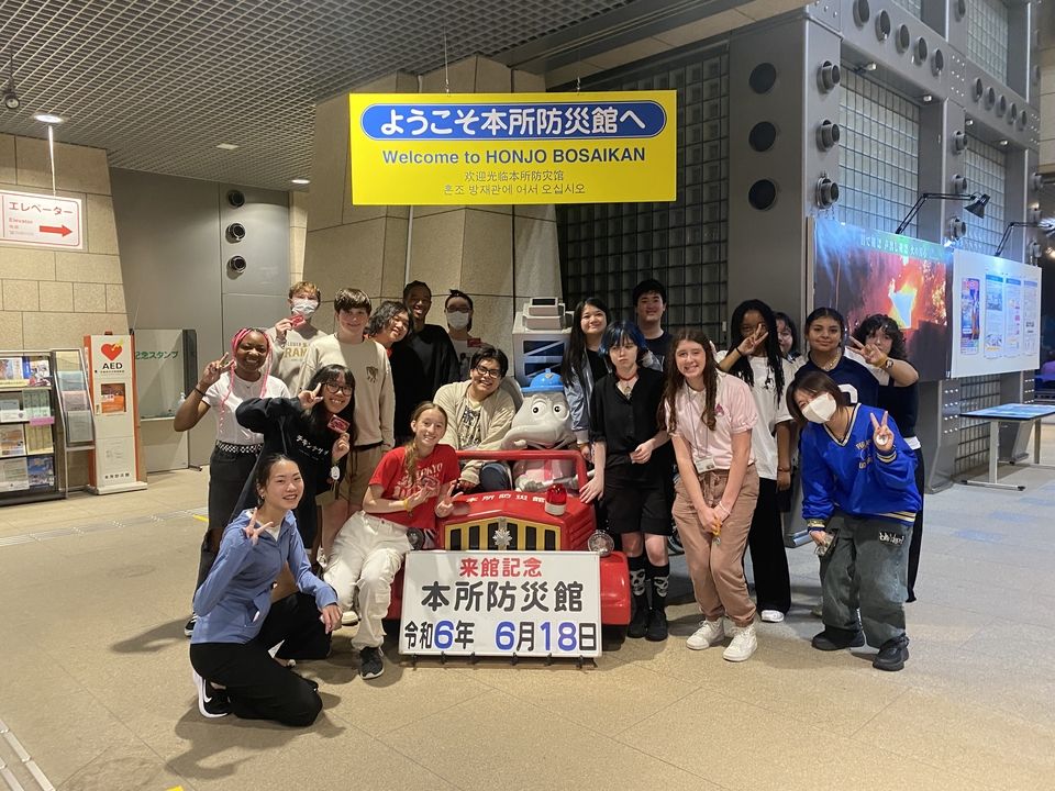 19 Global Navigators pose at Honjo Life and Safety Learning Center after learning about earthquakes, smoke escapes, typhoons, and urban flooding.