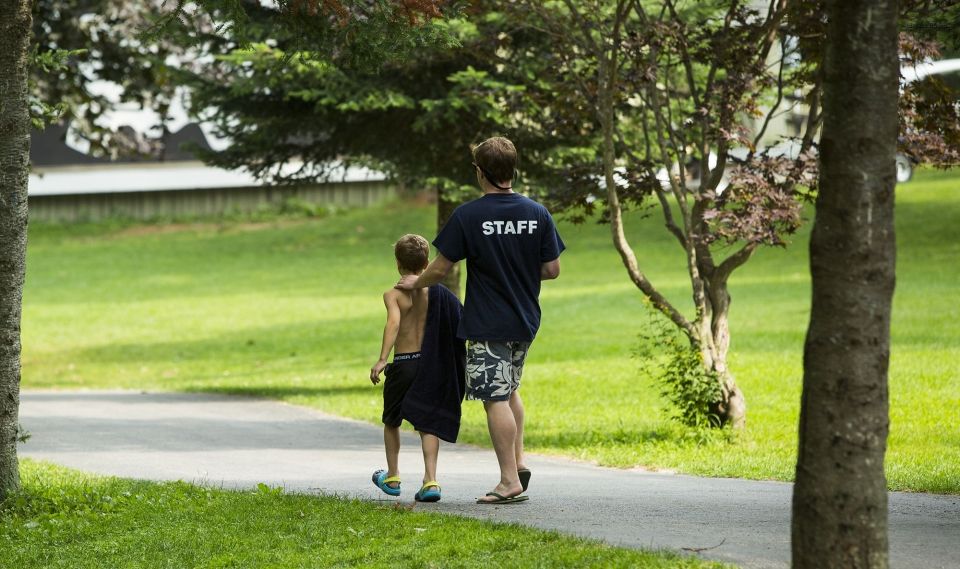 Counselor and kid walking down a path at camp